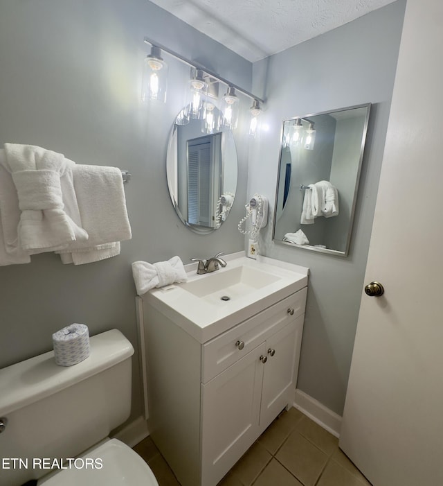 bathroom featuring tile patterned flooring, vanity, toilet, and a textured ceiling