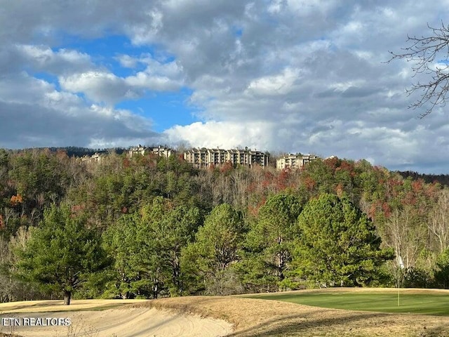 surrounding community with golf course view and a view of trees
