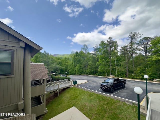uncovered parking lot with a view of trees
