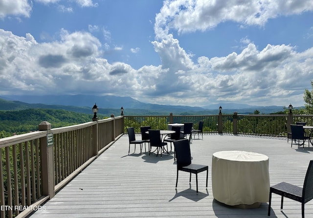 deck with a mountain view and outdoor dining area