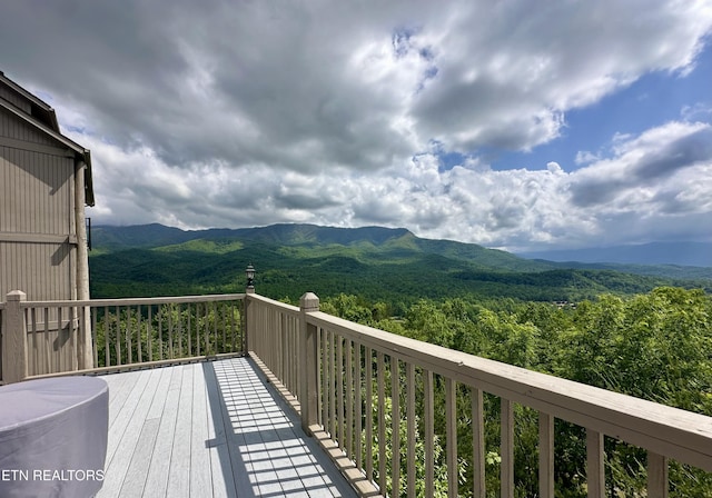 wooden deck with a forest view and a mountain view
