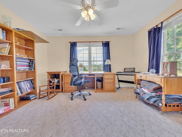 carpeted office space featuring a ceiling fan