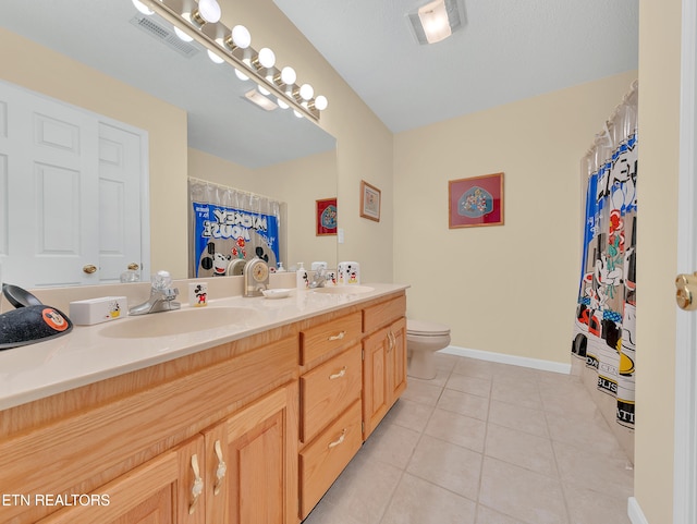 bathroom with tile patterned flooring, double vanity, toilet, and baseboards
