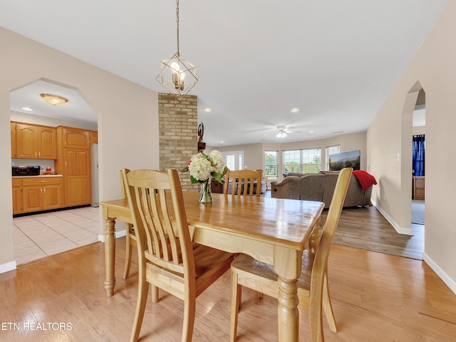 dining space featuring arched walkways, light wood-type flooring, recessed lighting, ceiling fan, and baseboards