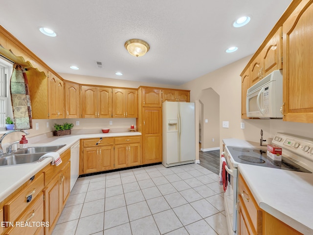 kitchen with white appliances, a sink, light countertops, recessed lighting, and light tile patterned floors