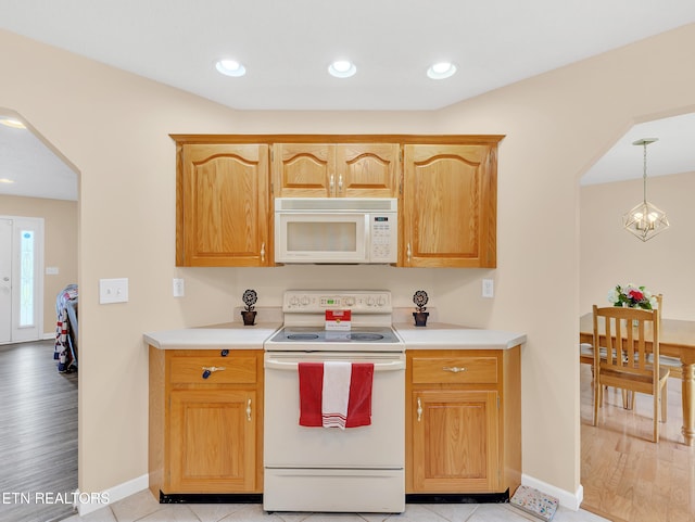 kitchen featuring white appliances, light countertops, baseboards, arched walkways, and recessed lighting