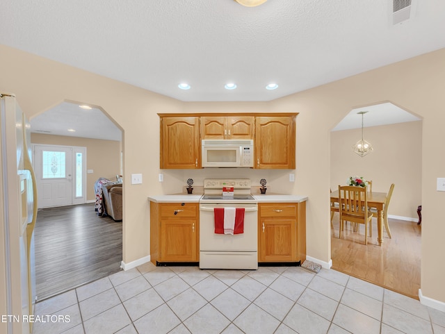kitchen featuring white appliances, arched walkways, light countertops, recessed lighting, and light tile patterned floors
