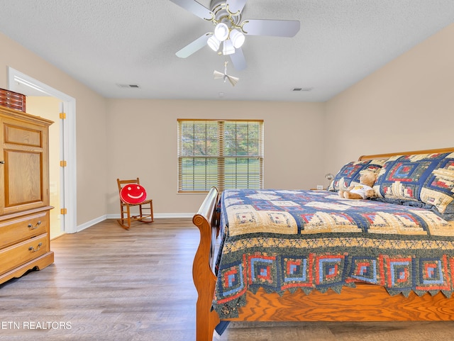 bedroom with wood finished floors, a textured ceiling, baseboards, and a ceiling fan