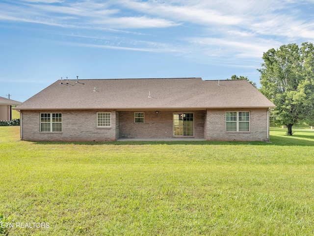 rear view of property with brick siding, a lawn, and roof with shingles