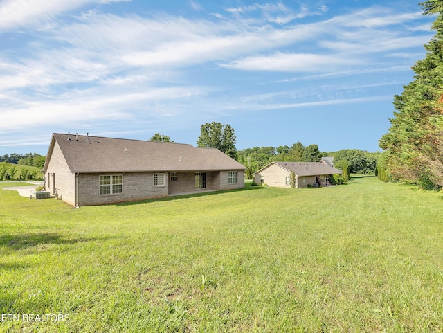 rear view of house featuring a lawn and central AC
