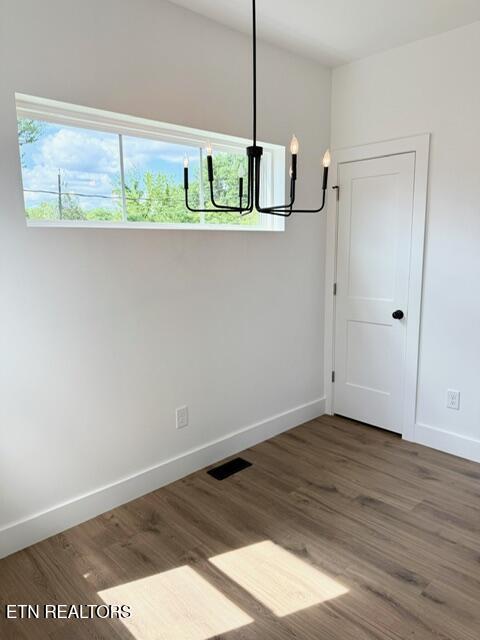 1118 NW Mercer St, Knoxville, TN 37921 - unfurnished dining area with a chandelier, baseboards, and wood finished floors