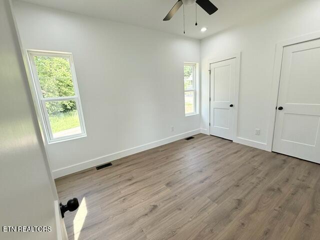 1118 NW Mercer St, Knoxville, TN 37921 - unfurnished bedroom with multiple windows, wood finished floors, baseboards, a ceiling fan, and recessed lighting