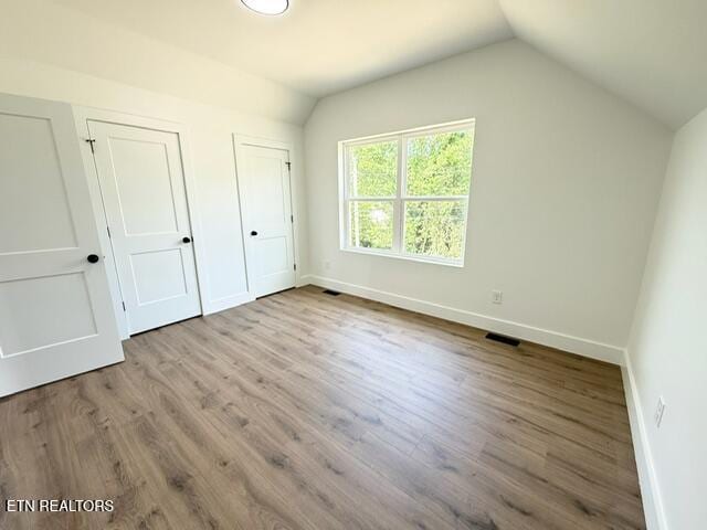1118 NW Mercer St, Knoxville, TN 37921 - unfurnished bedroom featuring vaulted ceiling, baseboards, two closets, and wood finished floors