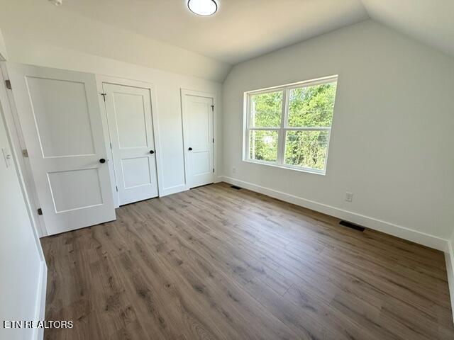 1118 NW Mercer St, Knoxville, TN 37921 - unfurnished bedroom with vaulted ceiling, multiple closets, baseboards, and wood finished floors