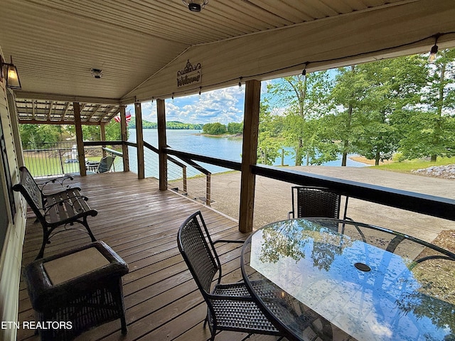 deck with a water view, outdoor dining space, and view of scattered trees