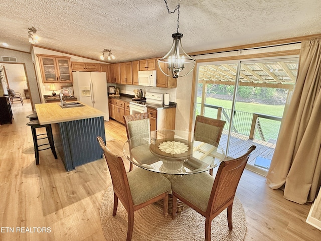 dining room featuring light wood-style flooring, a chandelier, a textured ceiling, and crown molding