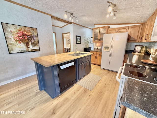 kitchen with white appliances, a sink, light wood finished floors, ornamental molding, and a center island with sink