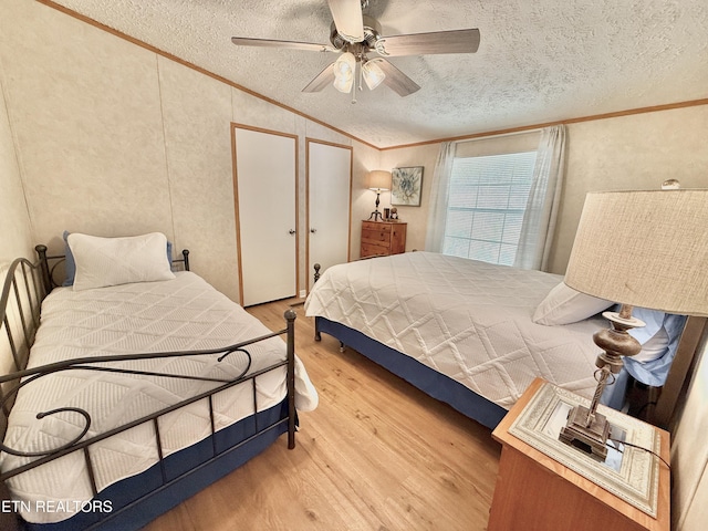 bedroom with ornamental molding, vaulted ceiling, wood finished floors, a textured ceiling, and a ceiling fan