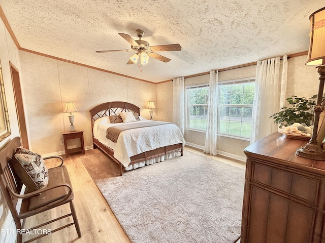 bedroom with crown molding, light wood finished floors, a textured ceiling, a ceiling fan, and baseboards