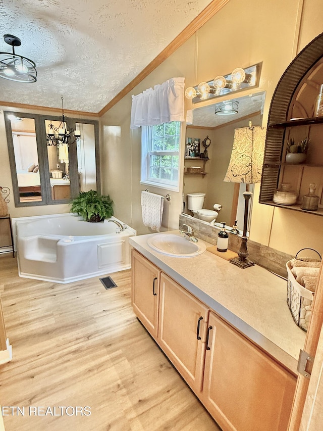 bathroom with wood finished floors, crown molding, vanity, a textured ceiling, and toilet