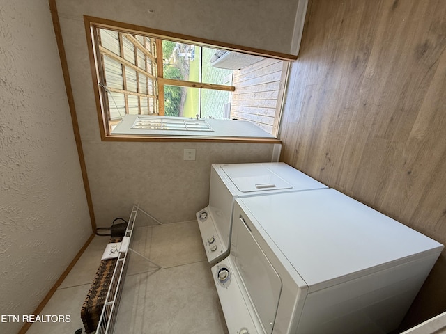 clothes washing area featuring washing machine and clothes dryer and a textured wall