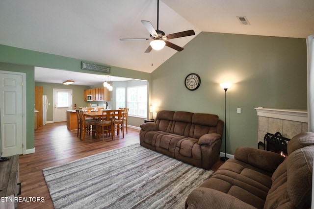 living room with ceiling fan, vaulted ceiling, wood finished floors, and baseboards