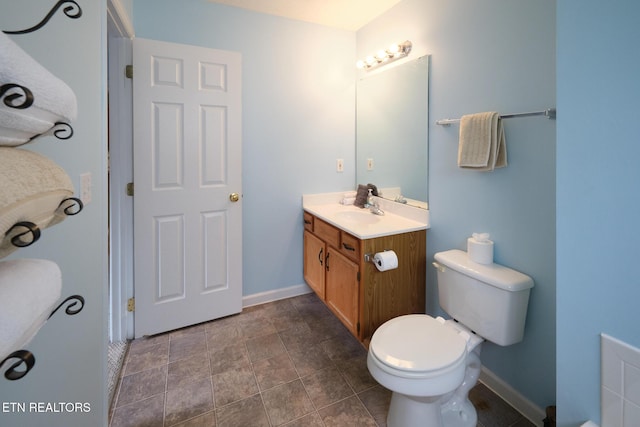 bathroom featuring vanity, toilet, baseboards, and stone finish floors