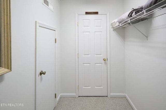 walk in closet featuring light colored carpet