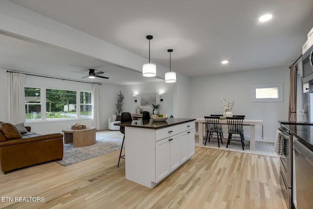 133 Nebraska Ave, Oak Ridge, TN 37830 - kitchen featuring open floor plan, a breakfast bar area, light wood finished floors, stainless steel appliances, and white cabinetry