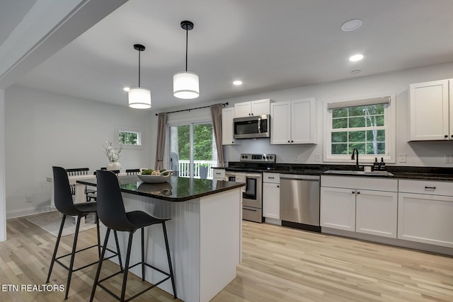 133 Nebraska Ave, Oak Ridge, TN 37830 - kitchen featuring appliances with stainless steel finishes, a sink, a breakfast bar area, light wood-style floors, and white cabinets