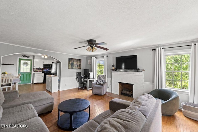 313 Lamar Ave, Clinton, TN 37716 - living room with a textured ceiling, arched walkways, a ceiling fan, a fireplace, and wood finished floors