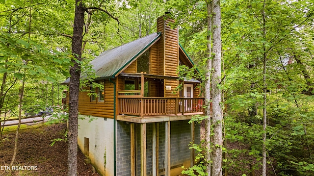 view of front of home with faux log siding, a chimney, and metal roof