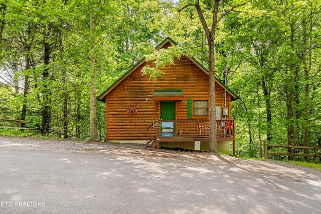view of front of house with a wooded view and fence