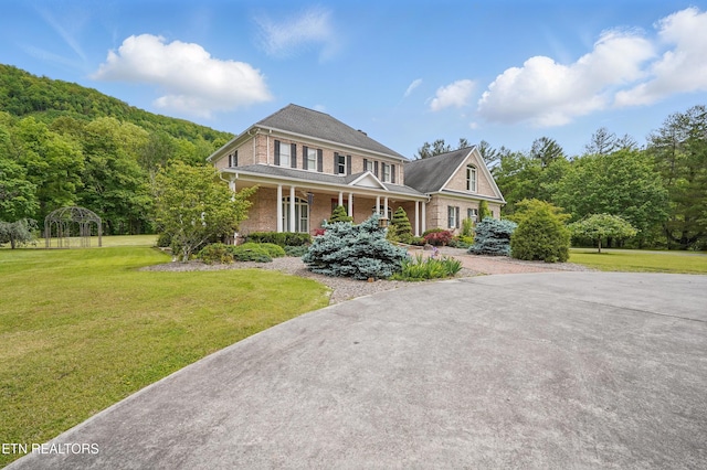 6005 Powell Valley Rd, Big Stone Gap, VA 24219 - view of front facade with covered porch, a front yard, brick siding, and a view of trees