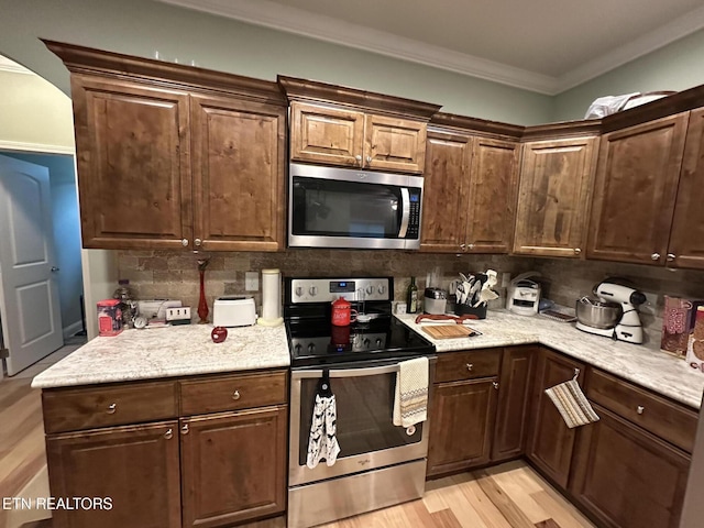 1923 Big Chiefs Skyview Dr, Sevierville, TN 37876 - kitchen featuring stainless steel appliances, backsplash, light wood-style flooring, crown molding, and light stone counters