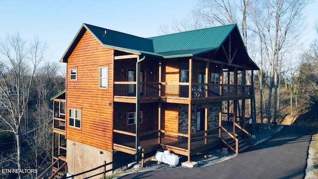 view of side of property featuring log veneer siding and metal roof