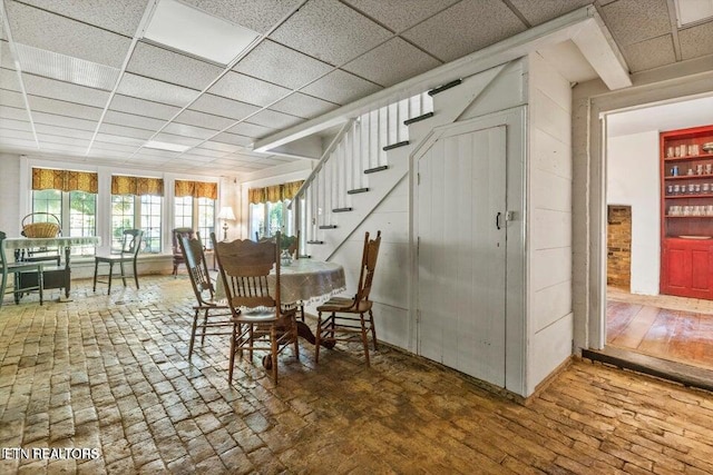 dining space with a paneled ceiling and stairway