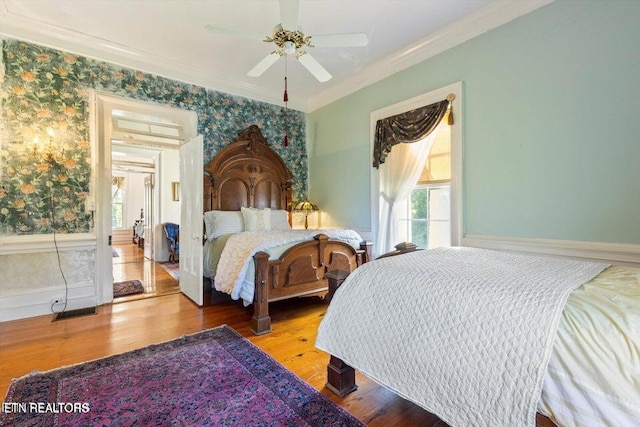 bedroom with wallpapered walls, crown molding, wood finished floors, and ceiling fan