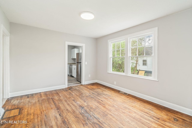 406 S Indiana Ave, Lafollette, TN 37766 - unfurnished bedroom featuring freestanding refrigerator, baseboards, wood-type flooring, and ensuite bath