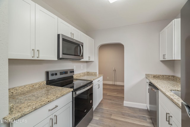 406 S Indiana Ave, Lafollette, TN 37766 - kitchen featuring stainless steel appliances, baseboards, light wood-style flooring, arched walkways, and white cabinetry
