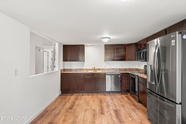 518 Church St, Vonore, TN 37885 - kitchen featuring appliances with stainless steel finishes, a sink, light wood-type flooring, dark brown cabinets, and light countertops