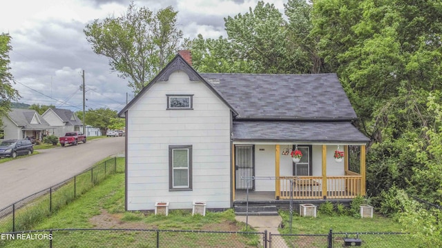 2918 Johnston St, Knoxville, TN 37921 - view of front of property with covered porch, a shingled roof, a fenced front yard, and a chimney
