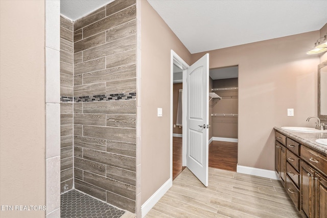2689 Spruce Loop, Crossville, TN 38555 - bathroom with double vanity, wood finished floors, a tile shower, a spacious closet, and baseboards