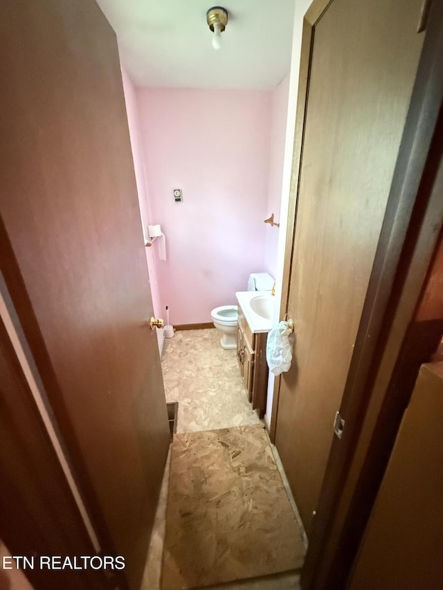 bathroom with toilet, vanity, and baseboards