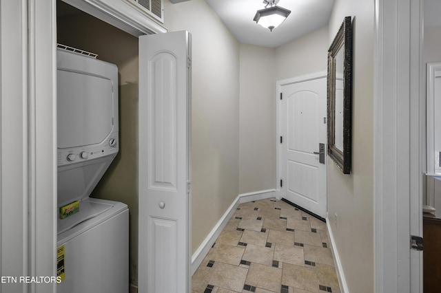 washroom featuring stacked washer and clothes dryer and baseboards
