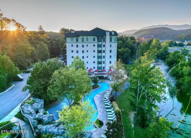 drone / aerial view of a pool area, apartment complex, and a mountain backdrop