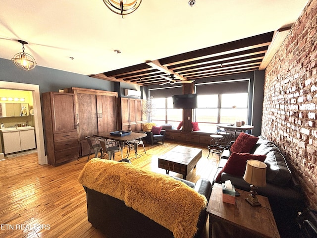 living area featuring beamed ceiling, a wall mounted air conditioner, and light wood-style floors