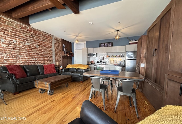 living area featuring brick wall, beamed ceiling, and light wood-style floors