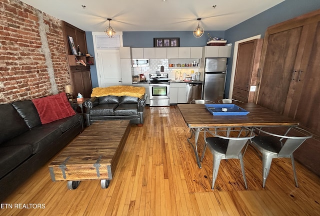 living room with light wood finished floors and brick wall