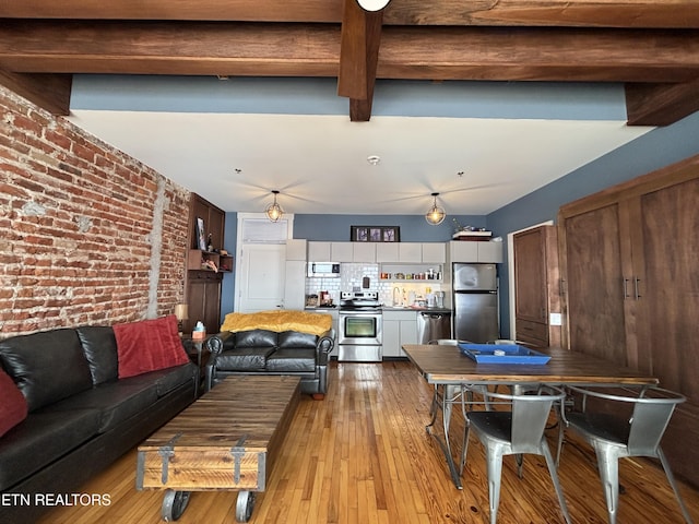 living area with brick wall, light wood-style floors, and beamed ceiling